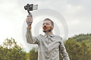 Portrait of businessman recording video presentation at smartphone with steadycam photo