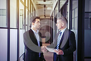 Portrait of businessman shaking his employee hands