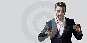 Portrait of businessman showing plastic credit card against grey background. Copyspace blank area for slogan or text
