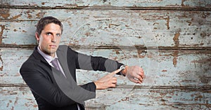 Portrait of businessman showing time on wristwatch against wooden wall