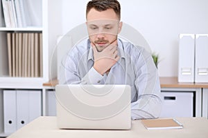 Portrait of businessman sitting at the desk in office workplace