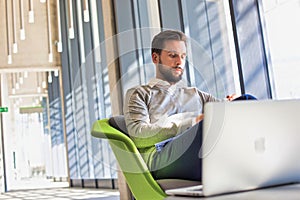 Portrait of Businessman sitting while using smartphone and drinking coffee in office lobby