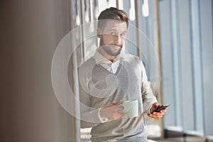 Portrait of Businessman sitting while using smartphone and drinking coffee in office lobby