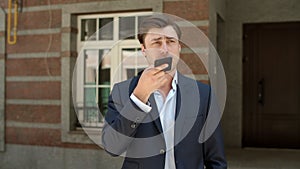 Portrait of businessman talking phone outdoors. Man having phone talk at street