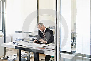 Portrait of businessman talking on telephone call while calculating