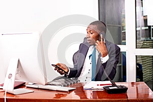 Businessman talking on telephone handset and holding mobile phone in office