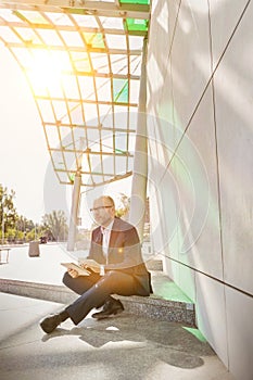 Portrait of businessman using digital tablet while sitting outside the office