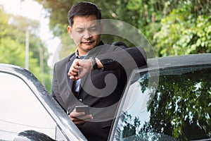 Portrait of businessman wearing suit and looking time with standing near his car