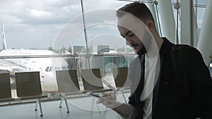 Portrait of businessman who is typing messege on his smartphone inside the airport.