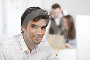 Portrait of businessman working on computer in office, looking c