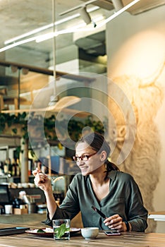Portrait of businesswoman having lunch in a cafe. Young female entrepreneur eating salad at lunch