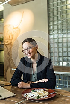 Portrait of businesswoman having lunch in a cafe. Young female entrepreneur eating salad at lunch