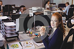 Portrait of businesswoman having snack while colleagues working in creative office