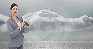 Portrait of businesswoman holding binoculars against sky