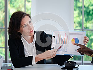 Portrait of businesswoman leader presenters showing growth graphics and taking a business conversation at office conference