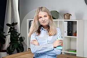 Portrait of businesswoman with mobile phone standing at office. young Caucasian businesswoman holding mobile phone in office.