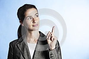 Portrait of businesswoman pointing upwards.