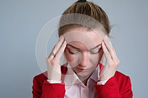 Portrait of a businesswoman in a red jacket with headache