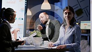 Portrait of businesswoman sitting at conference table in office meeting room working overtime