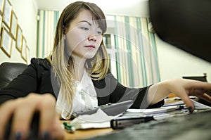 Portrait of a businesswoman sitting on her workplace in the office, typing, looking at pc screen.
