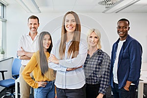 Portrait of businesswoman standing with group of startup colleagues in office