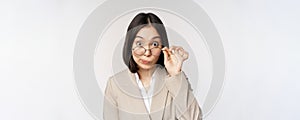 Portrait of businesswoman take-off glasses and looking surprised at camera, standing over white background