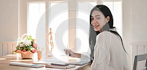 Portrait of businesswoman working on her project and smiling to the camera in comfortable room