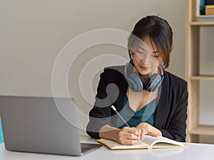 Portrait of businesswoman working from home with laptop, headphone and stationery