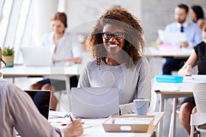 Portrait Of Businesswoman Working On Laptop In Busy Office