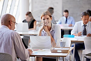 Portrait Of Businesswoman Working On Laptop In Busy Office