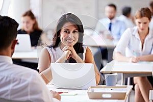 Portrait Of Businesswoman Working On Laptop In Busy Office