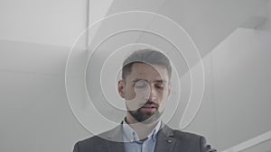 Portrait of busy businessman checking time as walking up the stairs. Bearded brunette Caucasian man having business