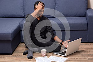 Portrait of busy worried man touching his head with hand, having headache, cant understand information given in Net, having cup
