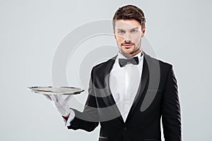 Portrait of butler in tuxedo holding empty tray