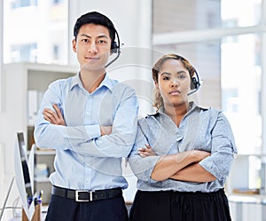 Portrait of call center colleagues. Business People working in customer service wearing headsets, arms crossed.Smiling