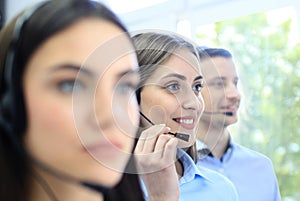 Portrait of call center worker accompanied by her team. Smiling customer support operator at work.