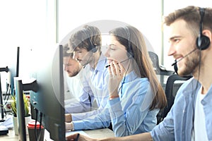 Portrait of call center worker accompanied by her team. Smiling customer support operator at work.