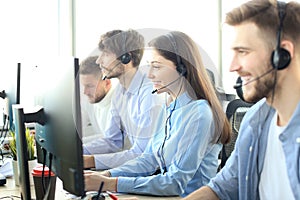 Portrait of call center worker accompanied by her team. Smiling customer support operator at work.