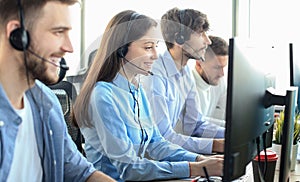 Portrait of call center worker accompanied by her team. Smiling customer support operator at work