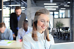 Portrait of call center worker accompanied by her team. Smiling customer support operator at work.