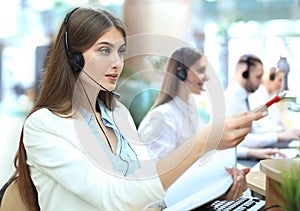 Portrait of call center worker accompanied by her team. Smiling customer support operator at work.