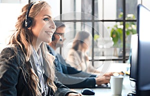 Portrait of call center worker accompanied by her team. Smiling customer support operator at work.