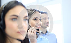 Portrait of call center worker accompanied by her team. Smiling customer support operator at work.