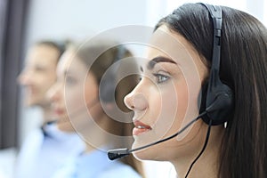 Portrait of call center worker accompanied by her team. Smiling customer support operator at work.