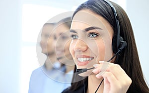 Portrait of call center worker accompanied by her team. Smiling customer support operator at work.