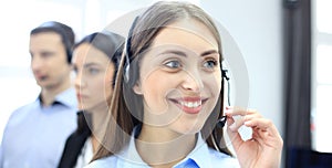 Portrait of call center worker accompanied by her team. Smiling customer support operator at work.