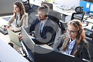 Portrait of call center worker accompanied by his team. Smiling customer support operator at work