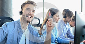 Portrait of call center worker accompanied by his team. Smiling customer support operator at work