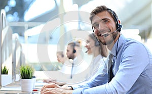 Portrait of call center worker accompanied by his team. Smiling customer support operator at work