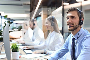 Portrait of call center worker accompanied by his team. Smiling customer support operator at work